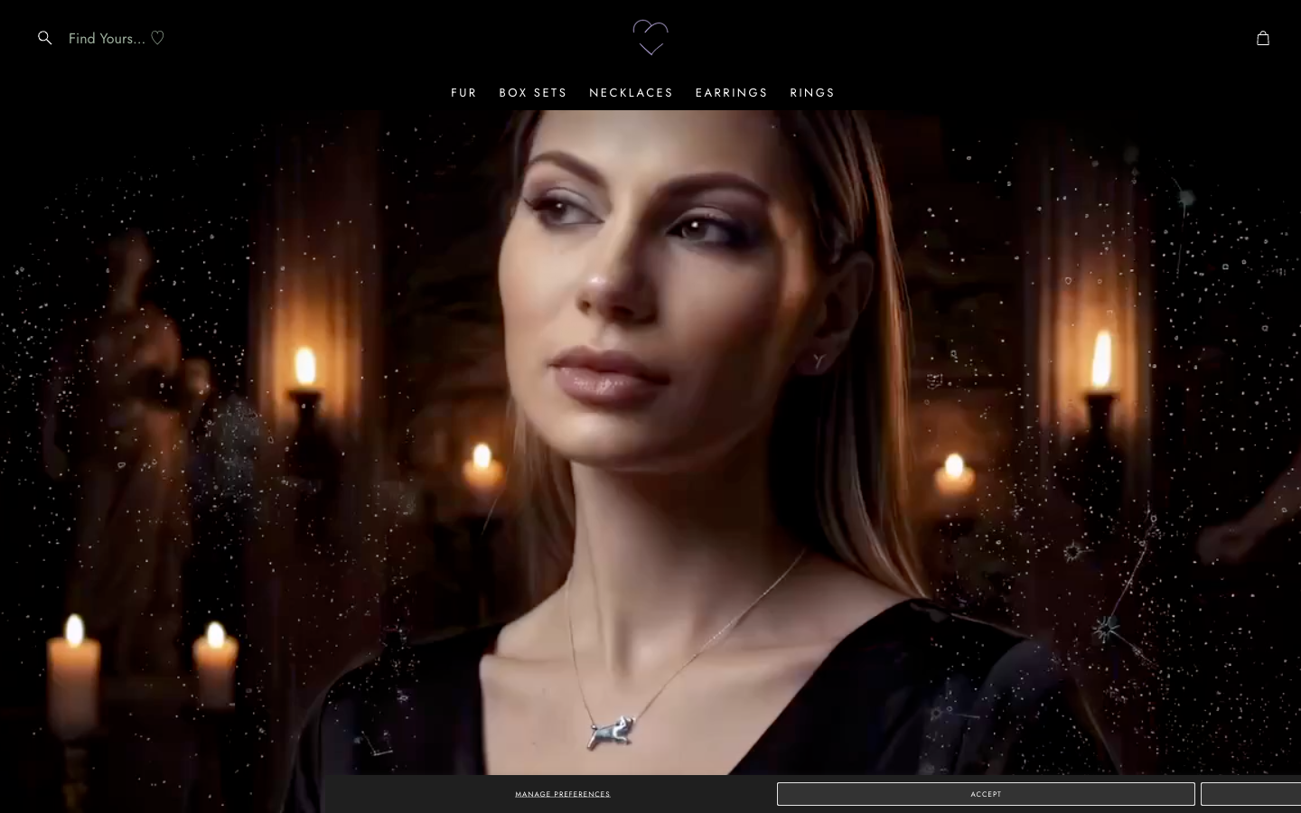 LoveYours Collection homepage — cinematic candle-lit portrait of a model wearing a sterling silver zodiac pendant, set against a constellation-flecked low-key interior. Heart-shaped wordmark above the navigation (FUR · BOX SETS · NECKLACES · EARRINGS · RINGS), search and basket controls in the corners.